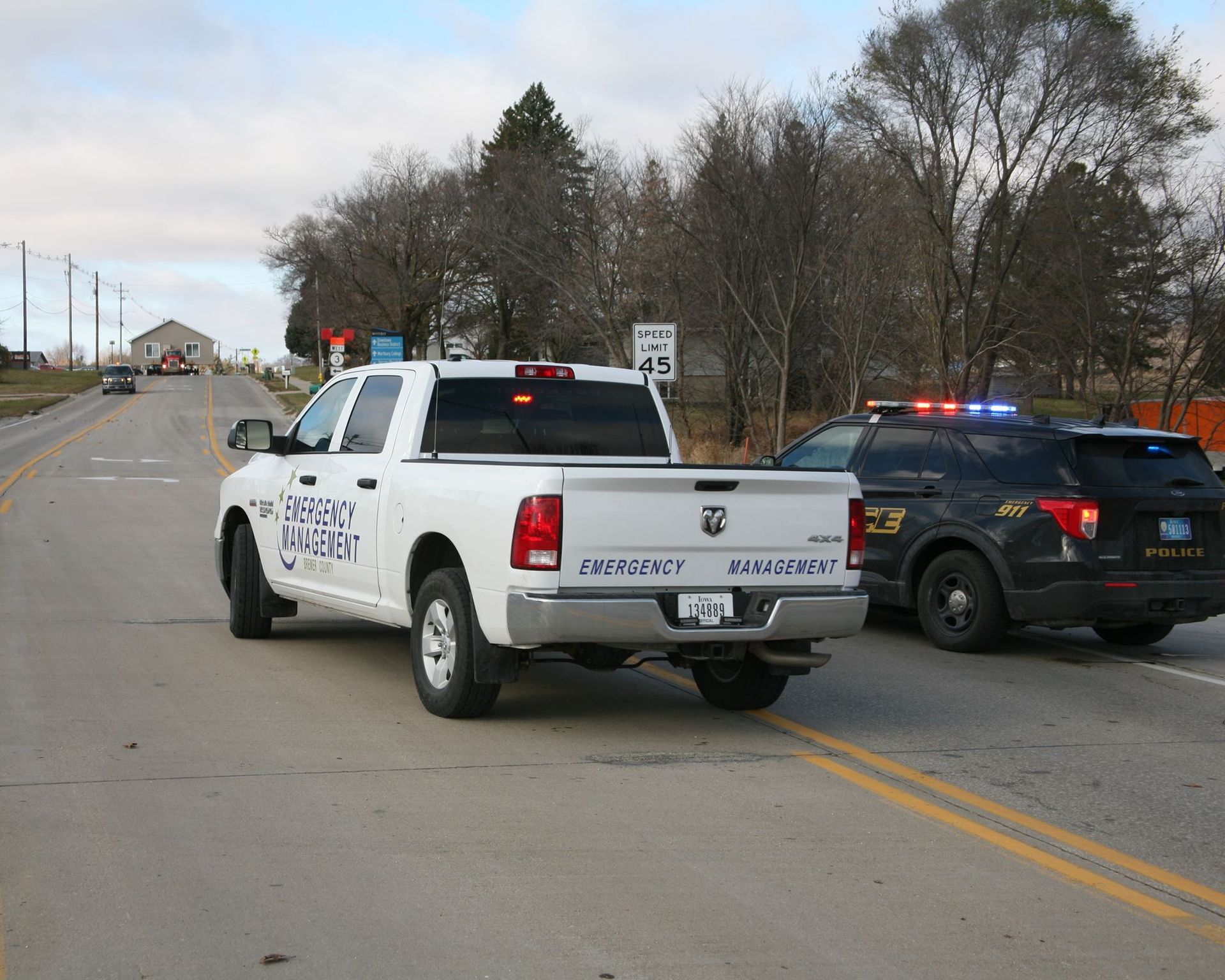 Police pickup truck and patrol car blocking a road with flashing lights in a rural area