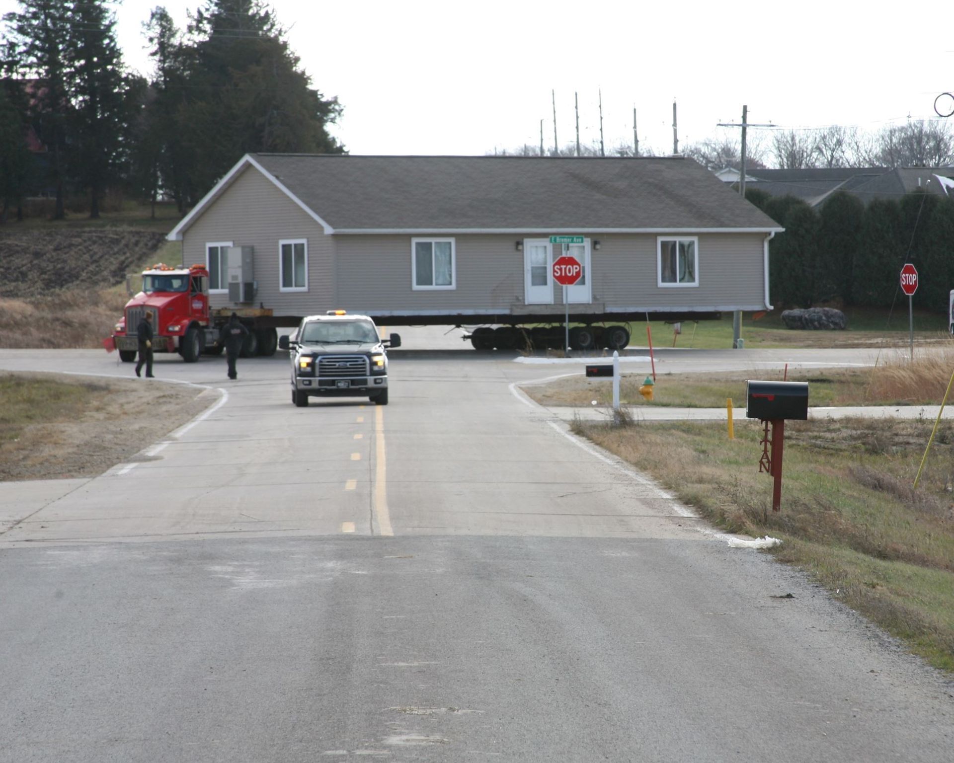 Rural road blocked by stop signs with a car and tractor near a small building
