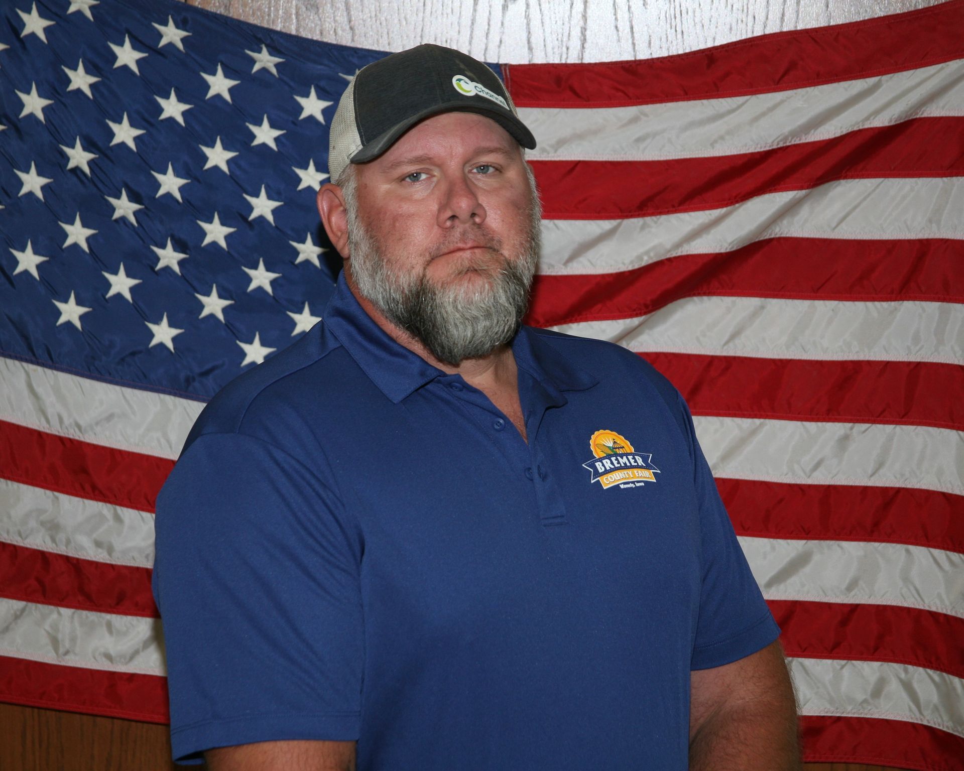 Man wearing a black cap and red polo shirt against a plain background