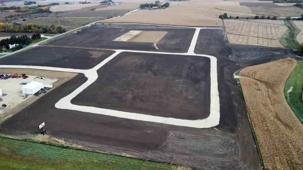 Aerial view of a dark, freshly graded field with pale dirt roads forming a new lot layout.