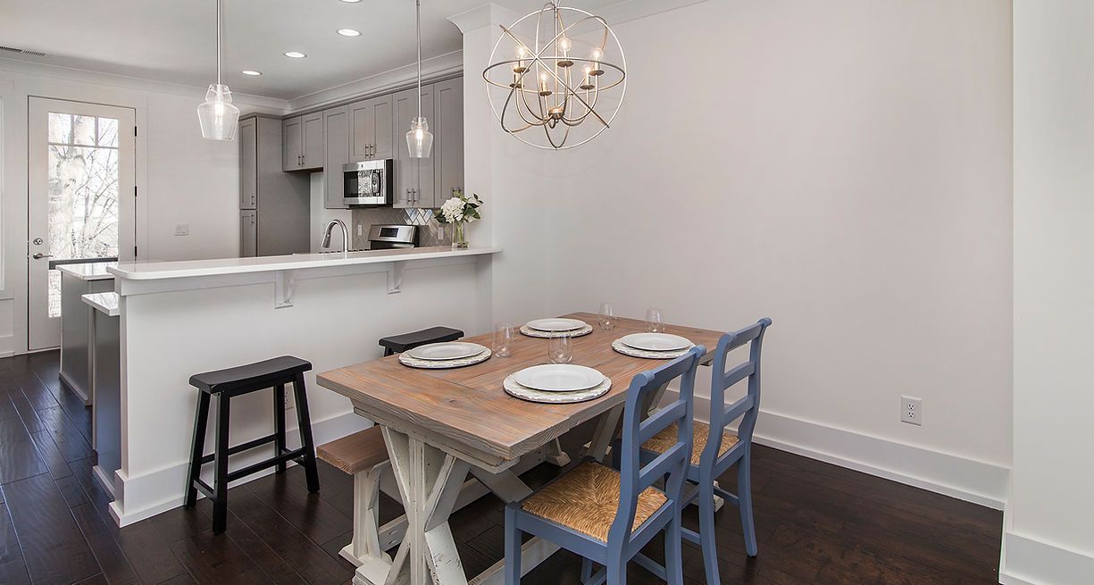 Dining area with wooden table, blue chairs, and kitchen with a bar.