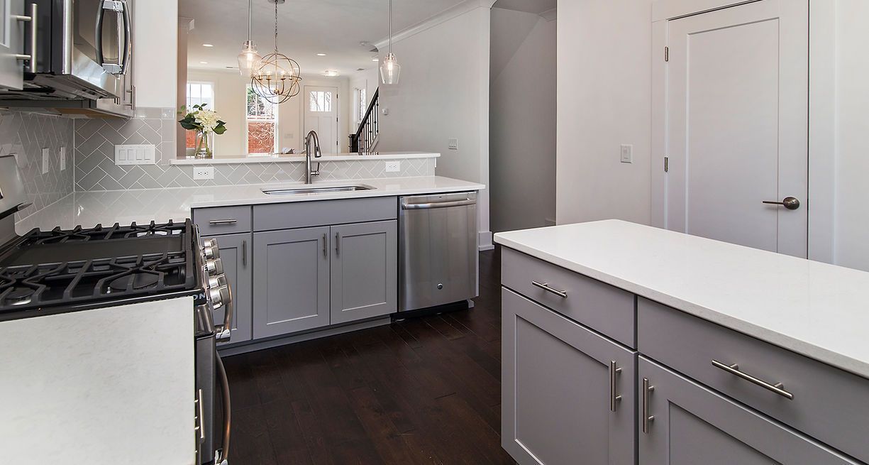 Modern kitchen with gray cabinets, stainless steel appliances, and a white island.