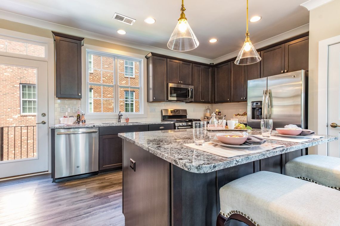 Kitchen with dark cabinets, stainless steel appliances, granite countertops, and an island with seating.