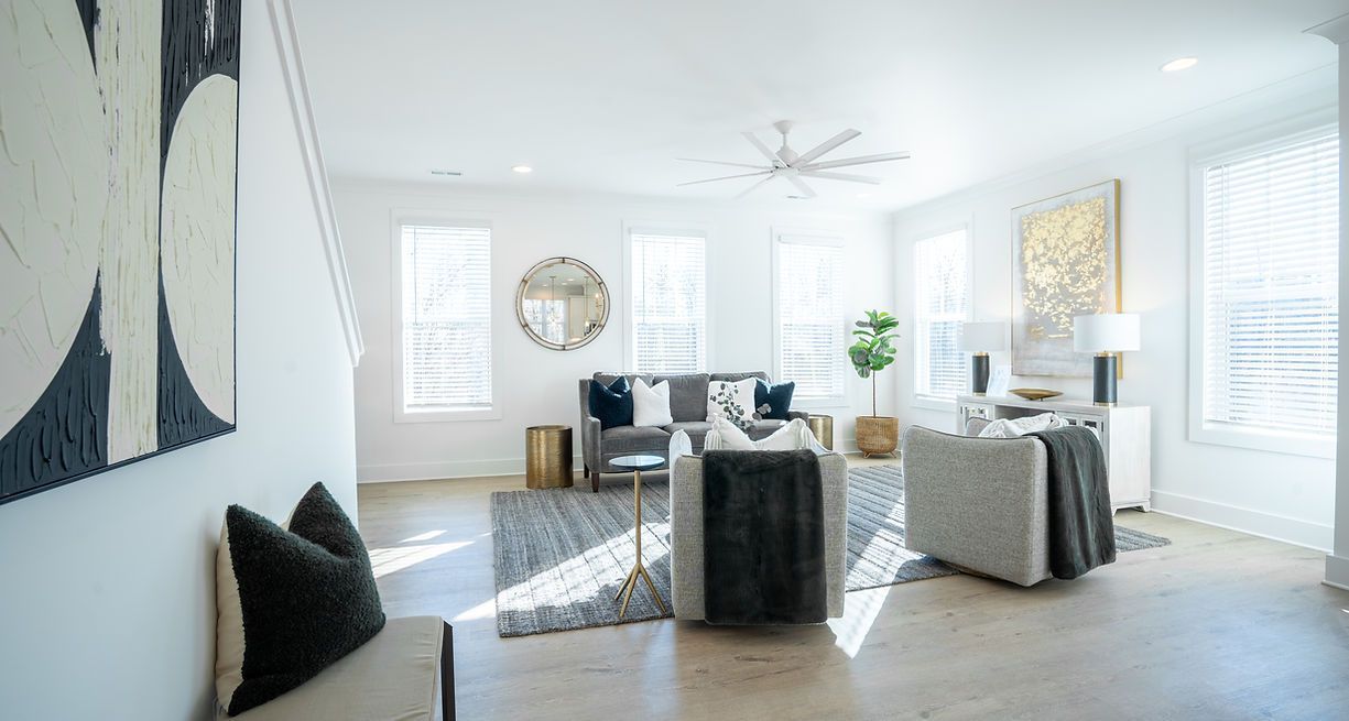 Bright, modern living room with neutral colors, art, and furniture. Natural light streams in from windows.