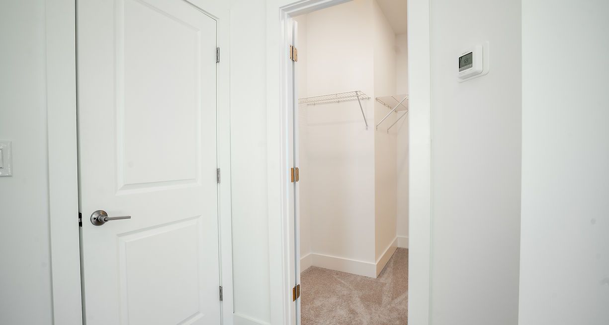 Hallway with a closet door on the left and a closet entrance on the right. White walls and doors.