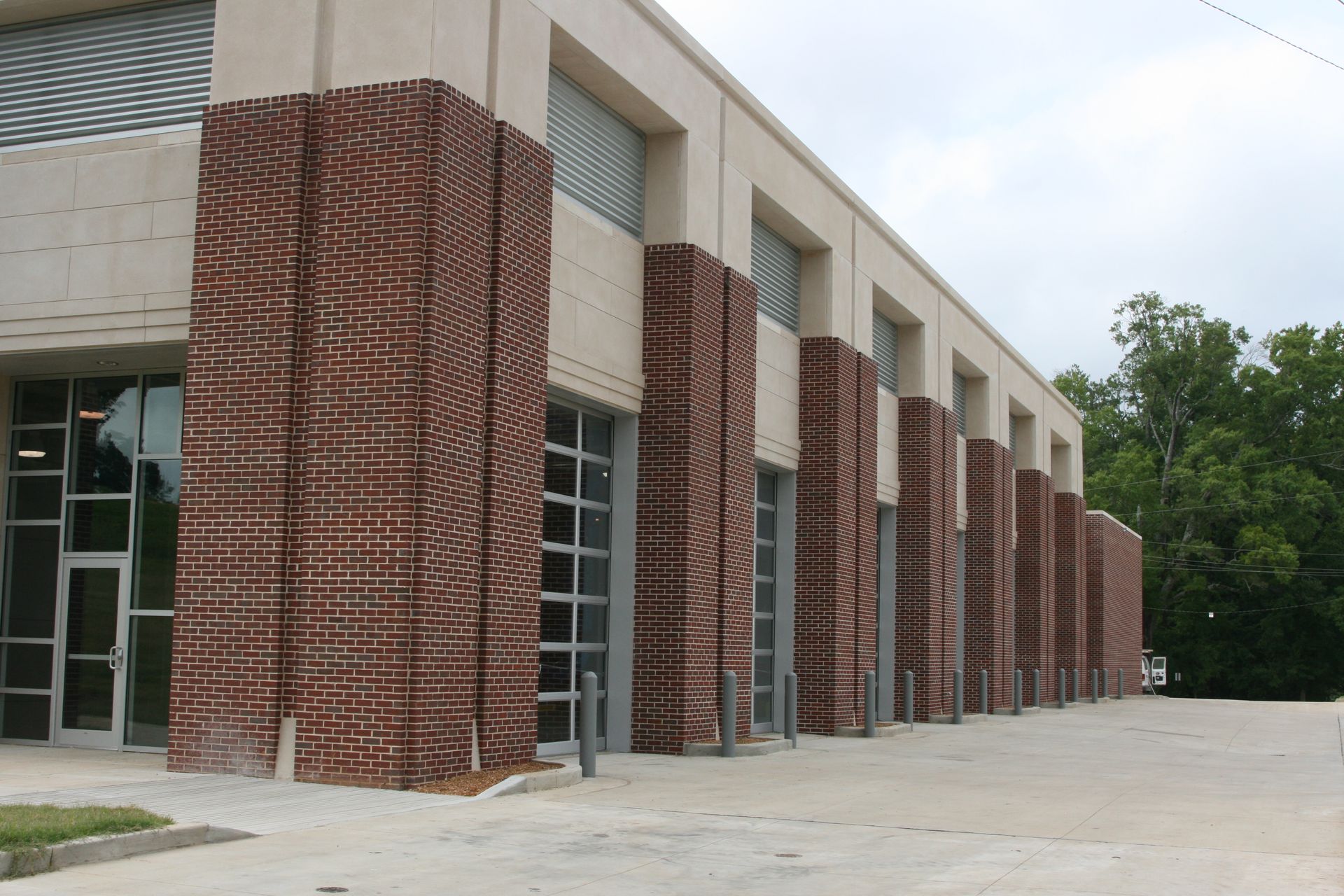 Modern brick-and-glass building with tall columns and a paved walkway outside