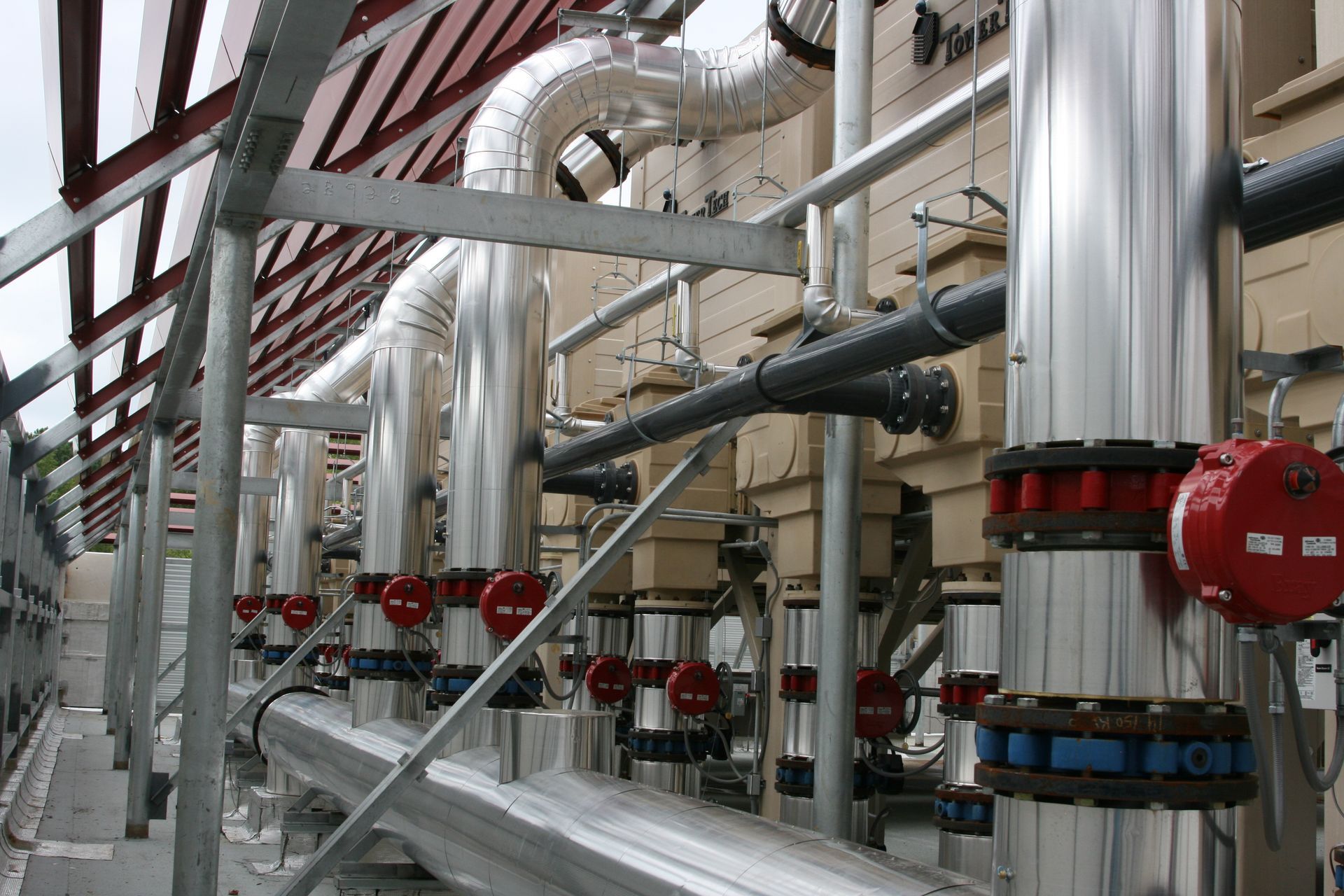 Industrial pipes and valves in a factory facility with silver ducting and red fittings
