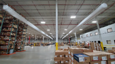 Spacious warehouse aisle with stacked boxes, tall shelving, and overhead industrial lights