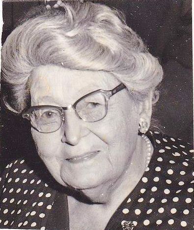 A black and white photo of an older woman wearing glasses and a polka dot shirt.