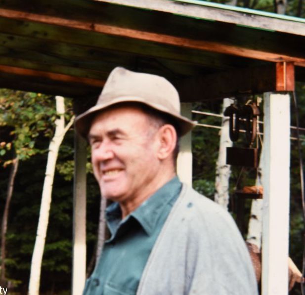A man wearing a hat and a cardigan is smiling