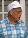 The man is wearing a plaid shirt and a white hat.