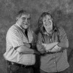 A man and a woman are posing for a picture with their arms crossed.