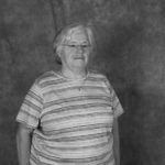 A black and white photo of an older woman wearing a striped shirt.