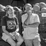 A man and a woman are sitting on the back of a truck.
