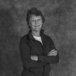A black and white photo of a woman with her arms crossed.