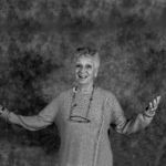 A black and white photo of a woman wearing glasses and a sweater.