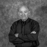 A black and white photo of a man with his arms crossed.
