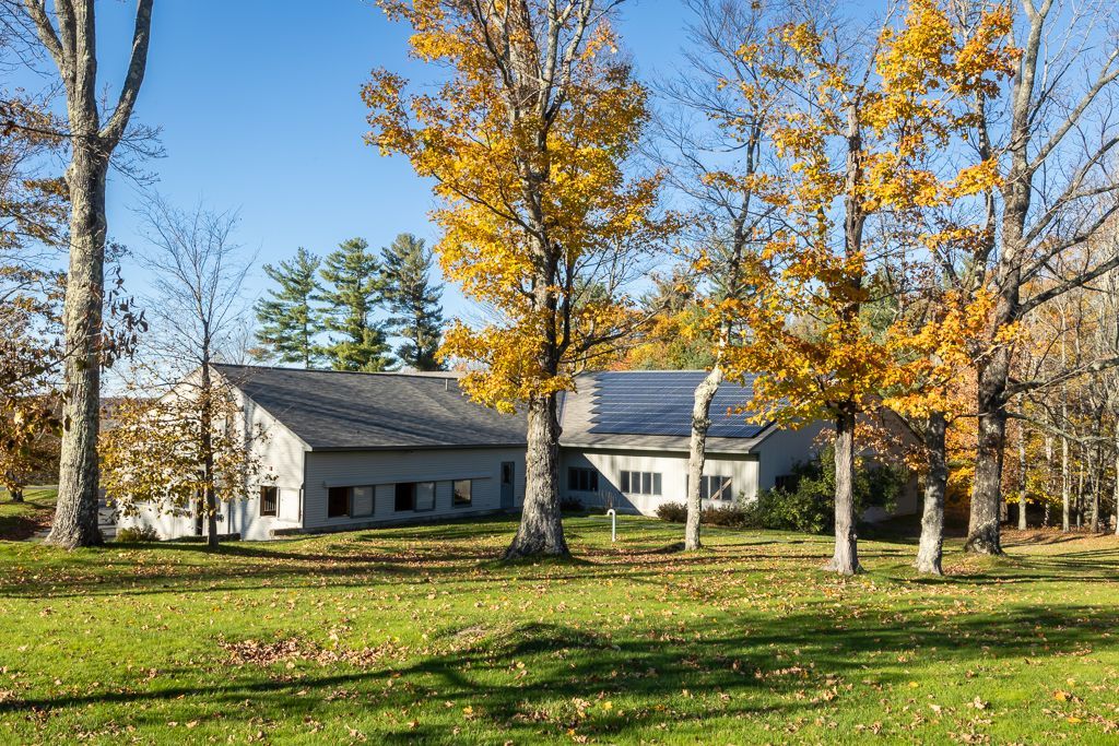 A house with solar panels on the roof is surrounded by trees