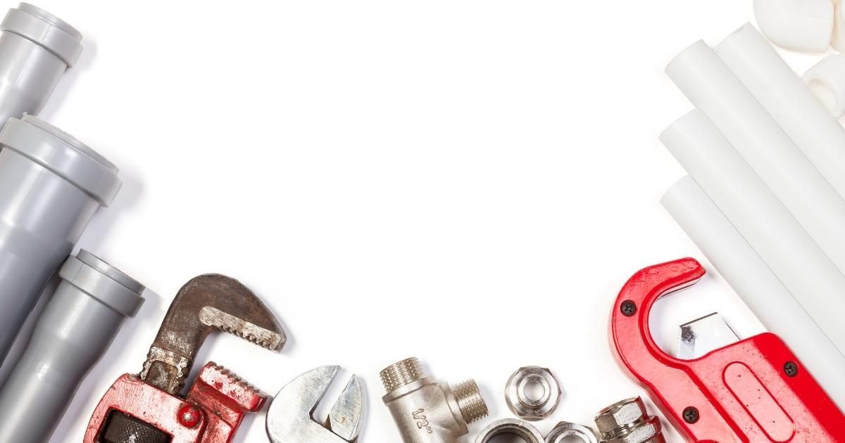 Assorted plumbing tools and pipe fittings, including a red pipe wrench and metal connectors on a white background