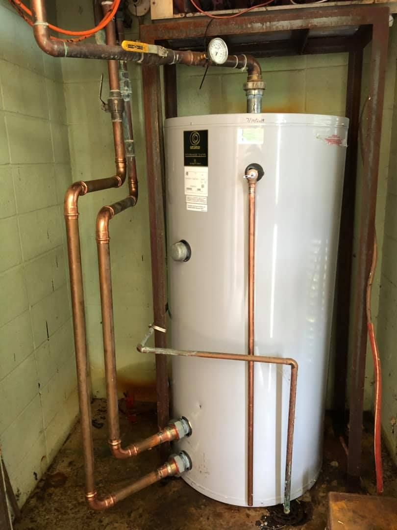 White water heater with copper plumbing in a utility room