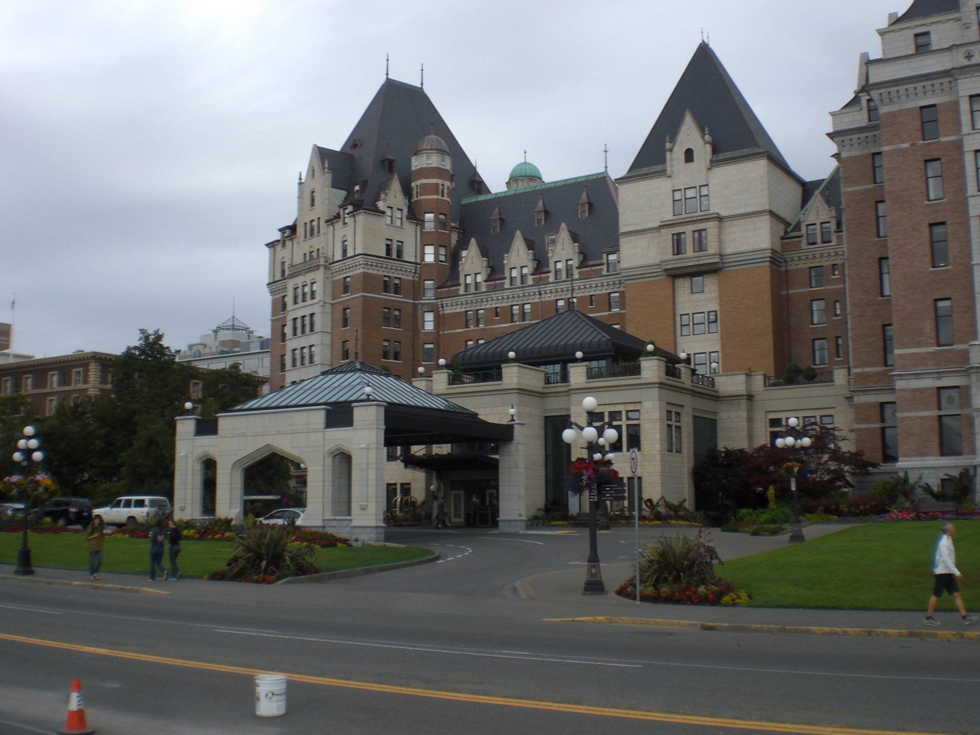 Fairmont Empress Hotel entrance, Victoria, BC; brick building, black roof, overcast day, people walking.