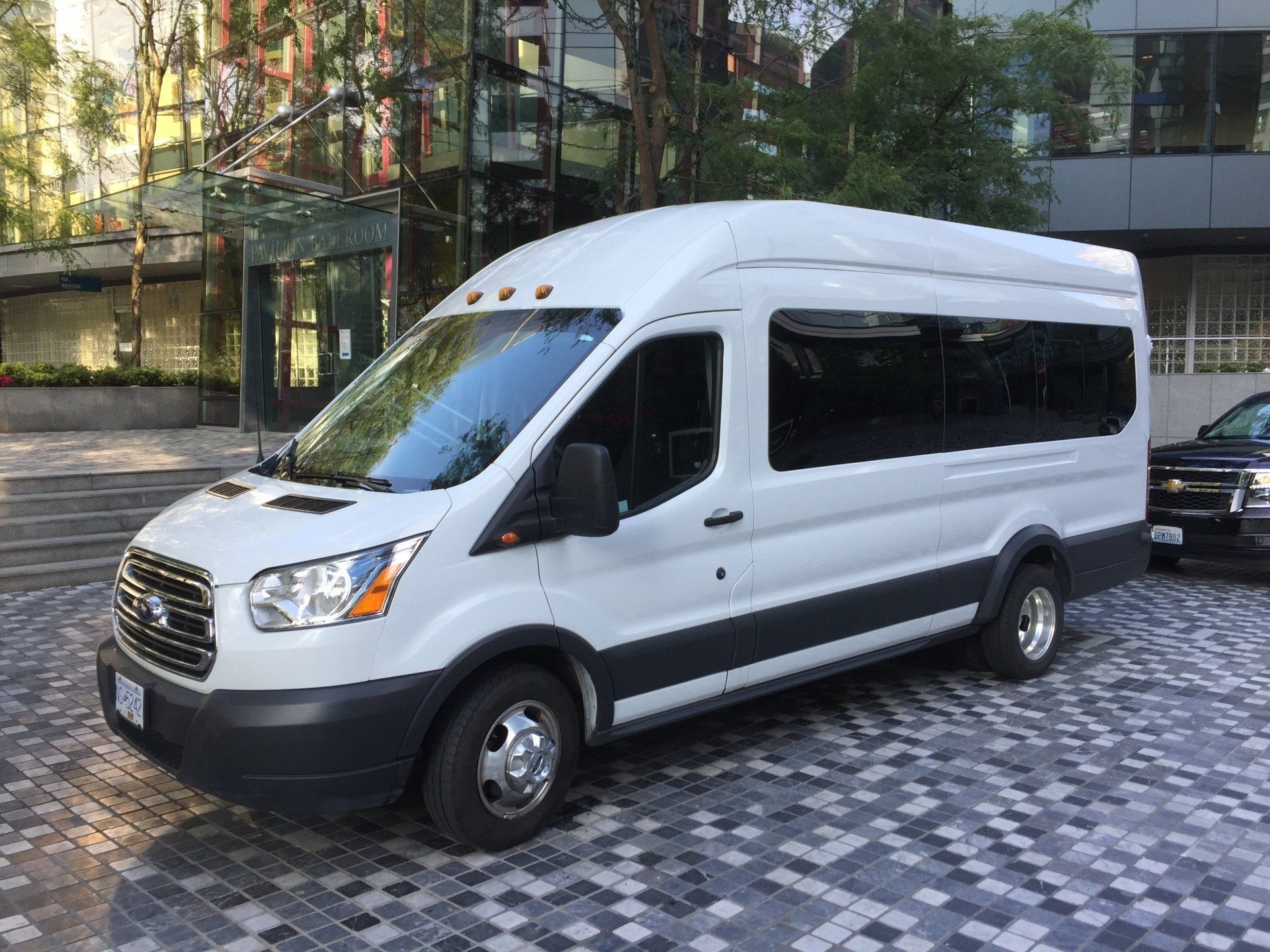 White passenger van parked on a city street in front of a building.