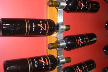 Wine bottles in a modern metal rack against a red wall at Fraser Valley vineyards