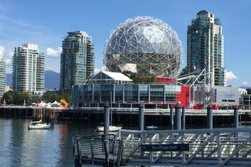 Science World with a spherical building, Vancouver, BC waterfront, with skyscrapers and water.