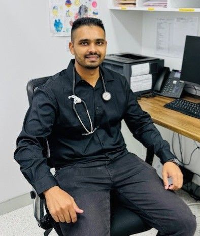 A woman is sitting at a desk with a stethoscope around her neck.