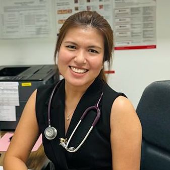 A woman is sitting at a desk with a stethoscope around her neck.
