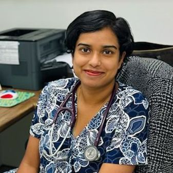 A woman is sitting in a chair with a stethoscope around her neck.