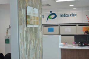 A woman is sitting at a desk in a medical clinic.