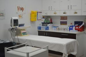 A doctor 's office with a table and a monitor.