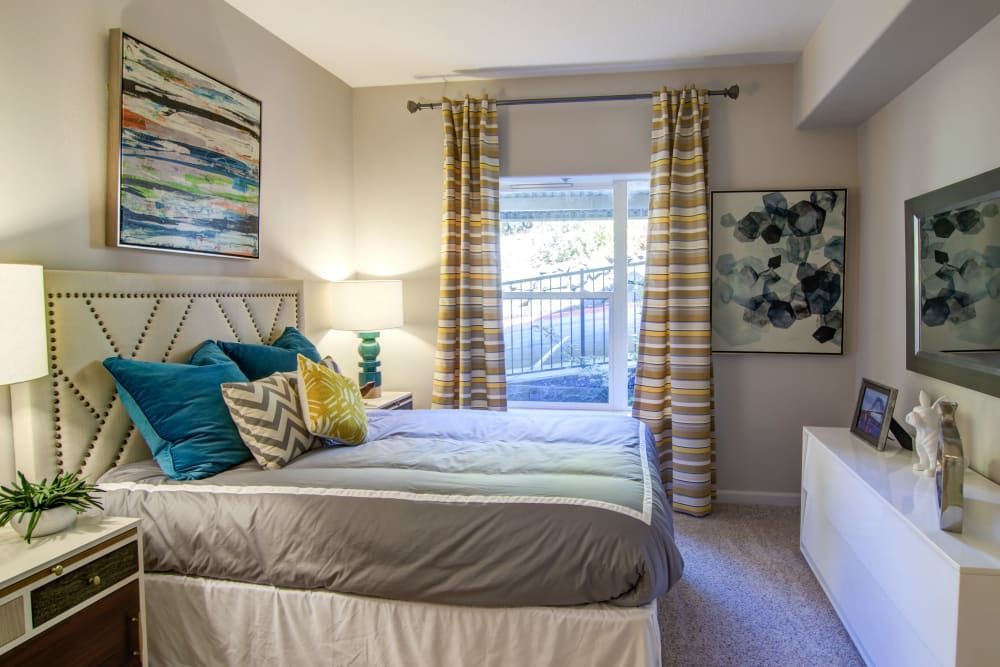 Bedroom with bed, art, window, and white dresser; gray and teal color scheme at Sofi at Forest Heights, offers apartments for rent in Portland, OR.