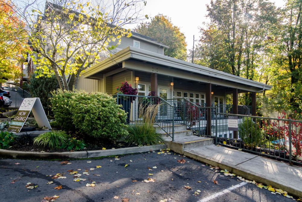 Building with porch and ramp, surrounded by trees at Sofi at Forest Heights, offers apartments for rent in Portland, OR. Sign on left.