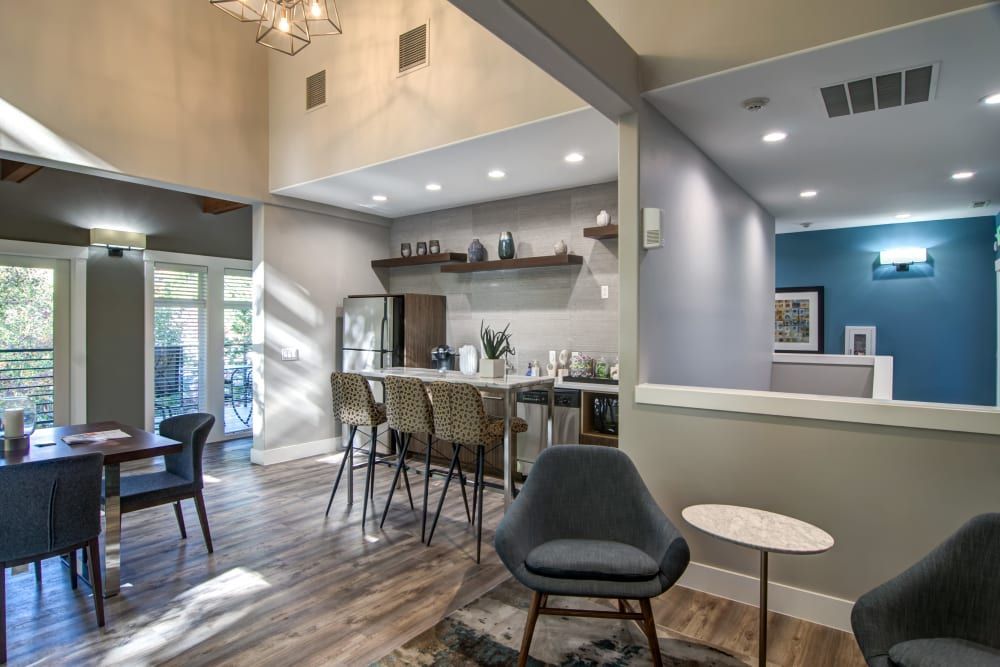 Modern interior with dining table, kitchen bar, chairs, and blue accents at Sofi at Forest Heights, offers apartments for rent in Portland, OR.