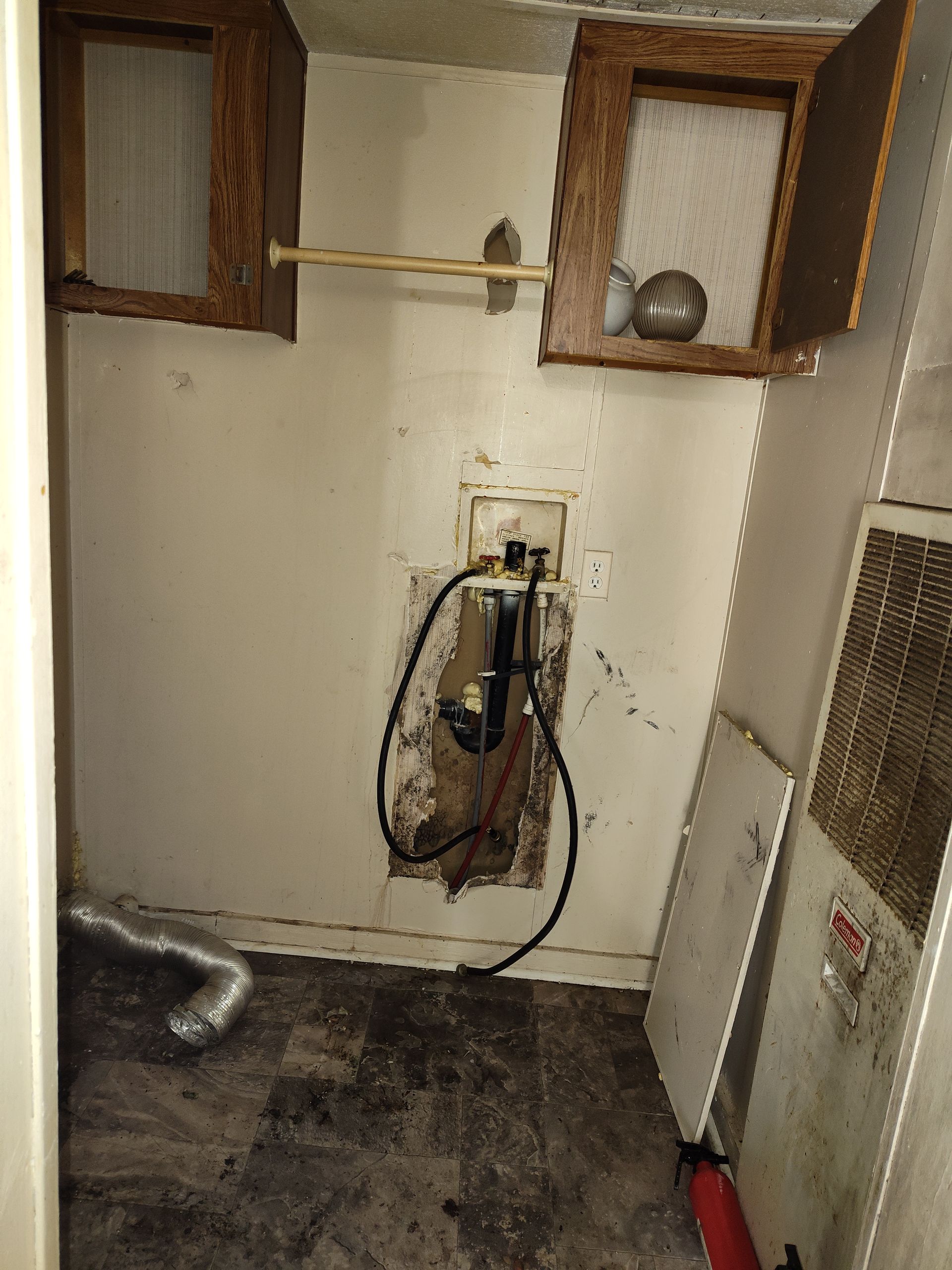 A dirty room with a fire extinguisher on the floor.