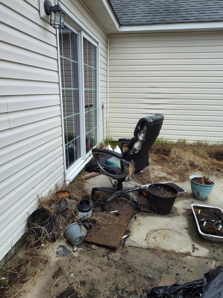 A patio with a chair and potted plants in front of a house.