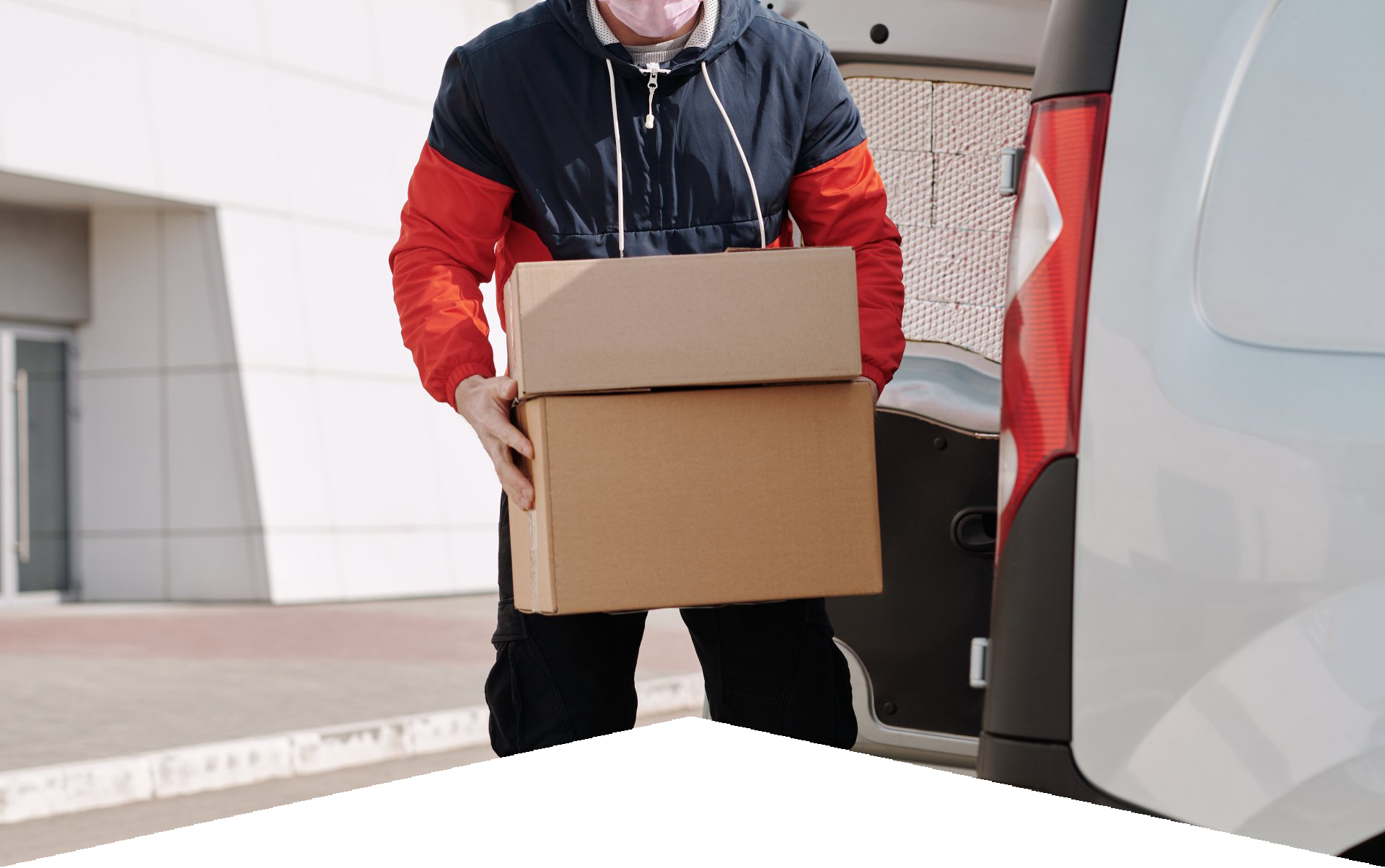 A delivery man is carrying a cardboard box into the back of a van.