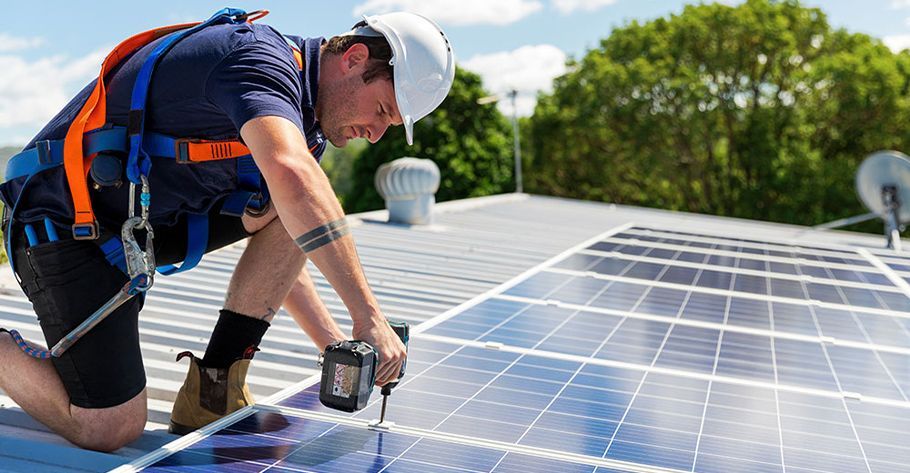 An electrician is installing solar panels on the roof of a building.