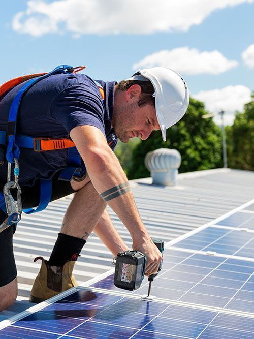 A man is installing solar panels on the roof of a building.