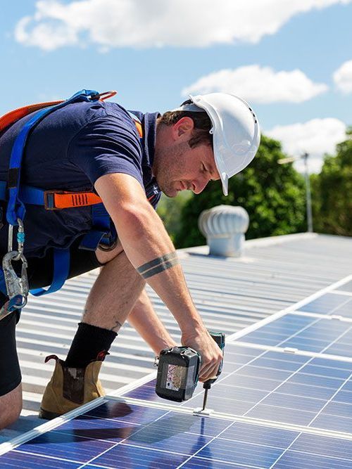 A man is installing solar panels on the roof of a building.