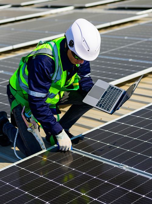 A man is working on a solar panel with a laptop.