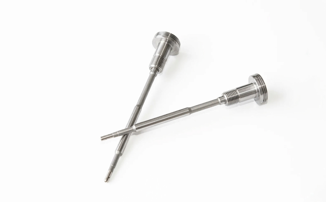 Dos tornillos de metal plateado cruzados sobre un fondo blanco.