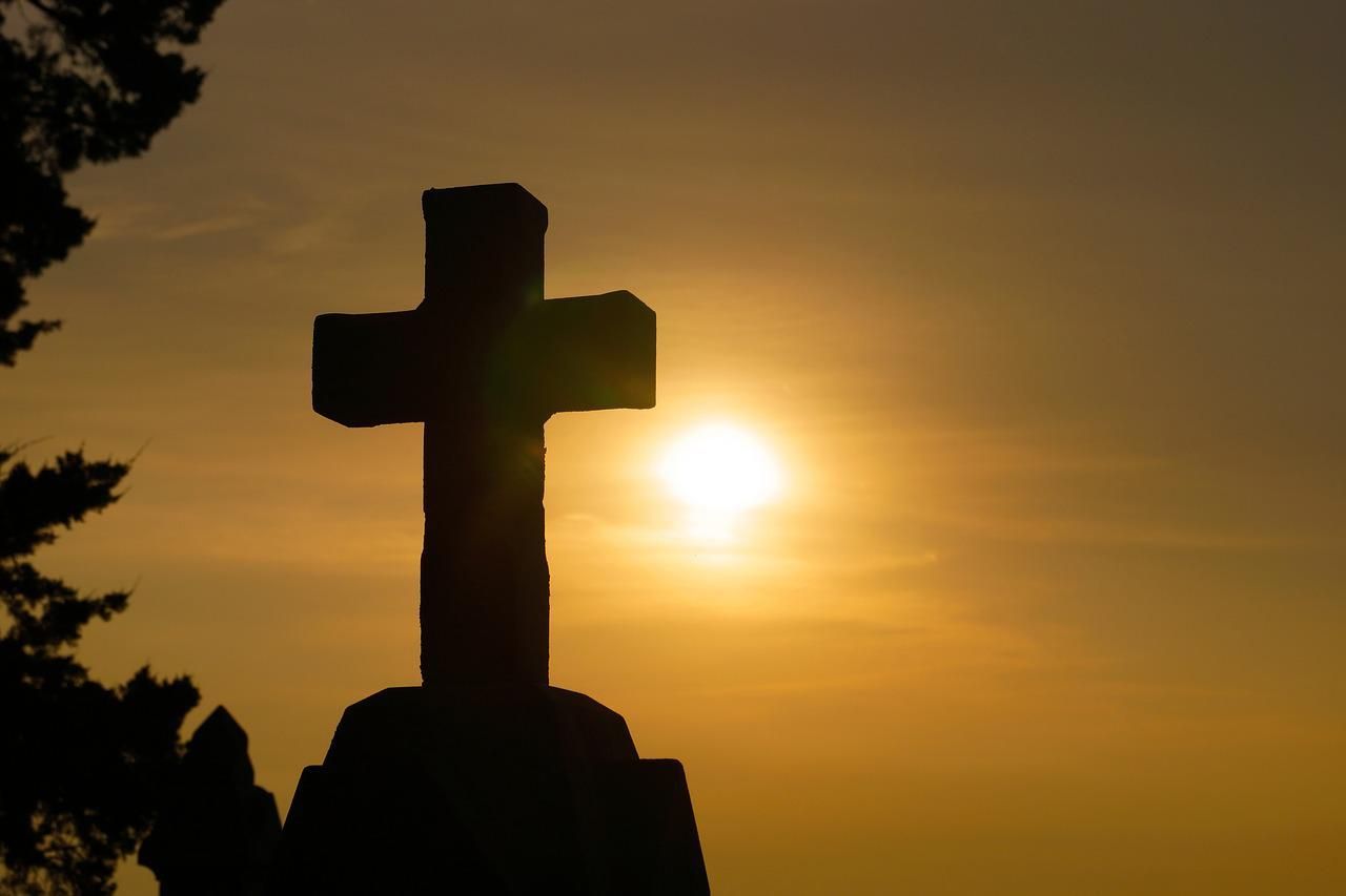 A cross is silhouetted against a sunset sky.