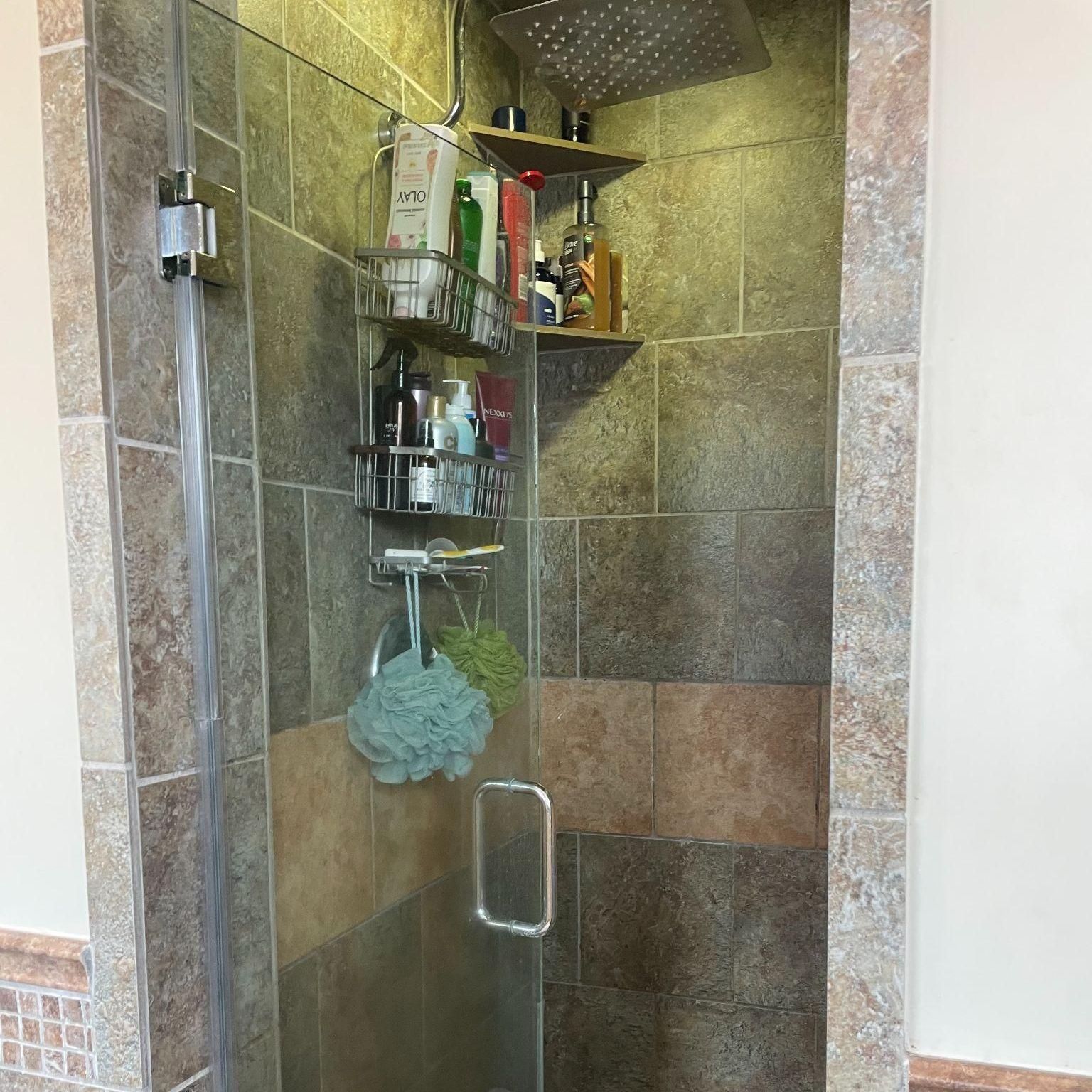 Tiled walk-in shower with rain head and built-in shelving – bathroom remodeling contractor service