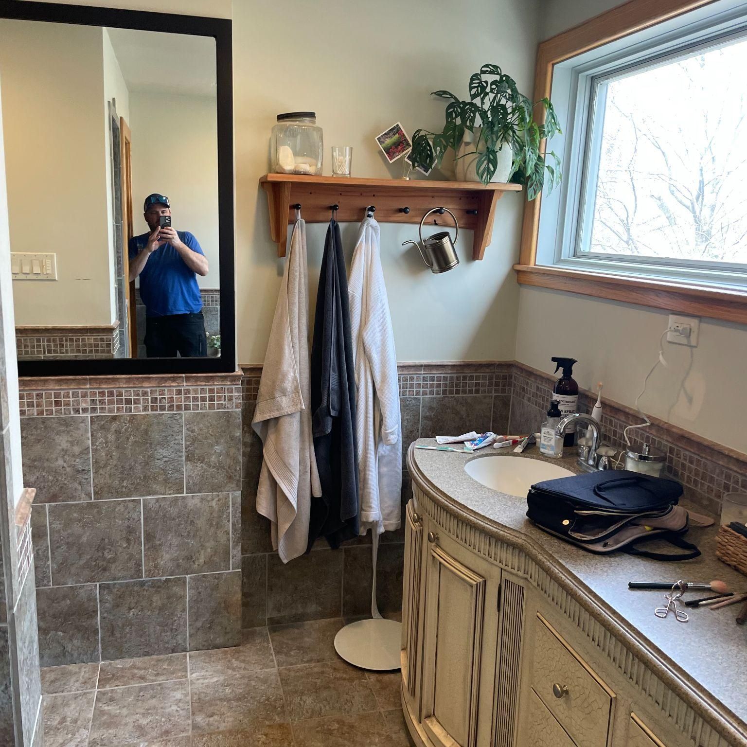 Bathroom vanity installation with mirror, tiled walls, and shelving – general home repair services.