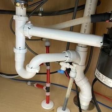 Complex under sink plumbing with disposal and water lines – plumbing and faucet installation.