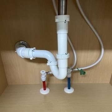 Under sink plumbing with hot and cold water valves – professional faucet and plumbing installation.

