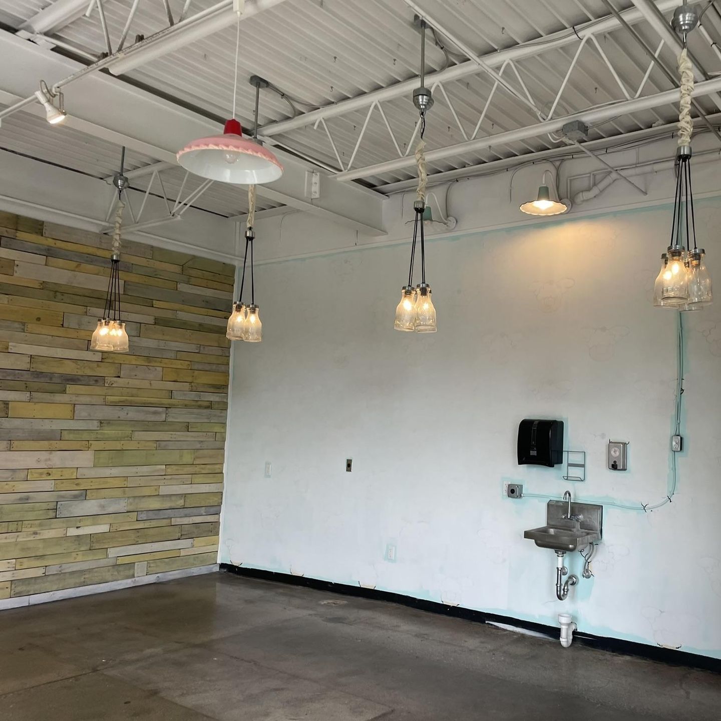 Exposed ceiling with pendant lighting and wall-mounted utility sink – electrical and lighting installation.